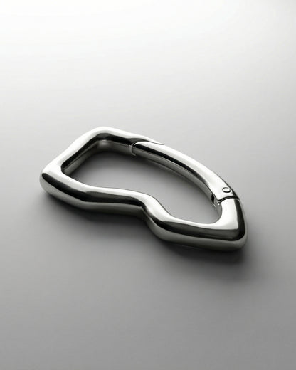 Shiny metallic object with a curved, abstract shape on a light background.