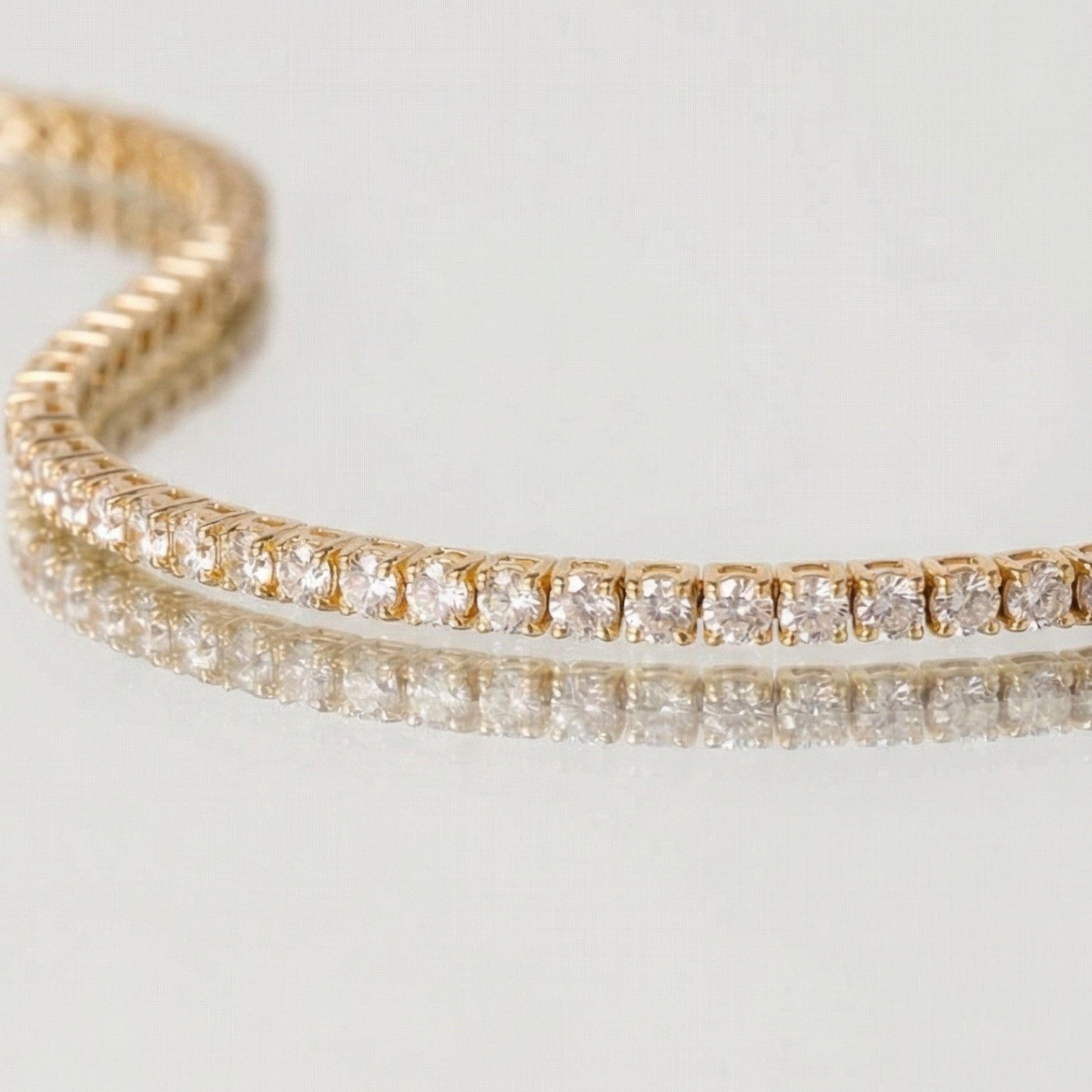 Gold bracelet with diamond stones on a light gray background