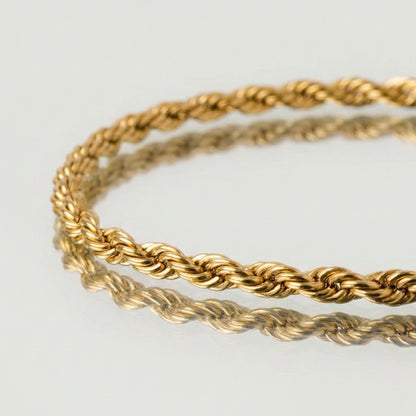 Two gold rope bracelets on a light gray background