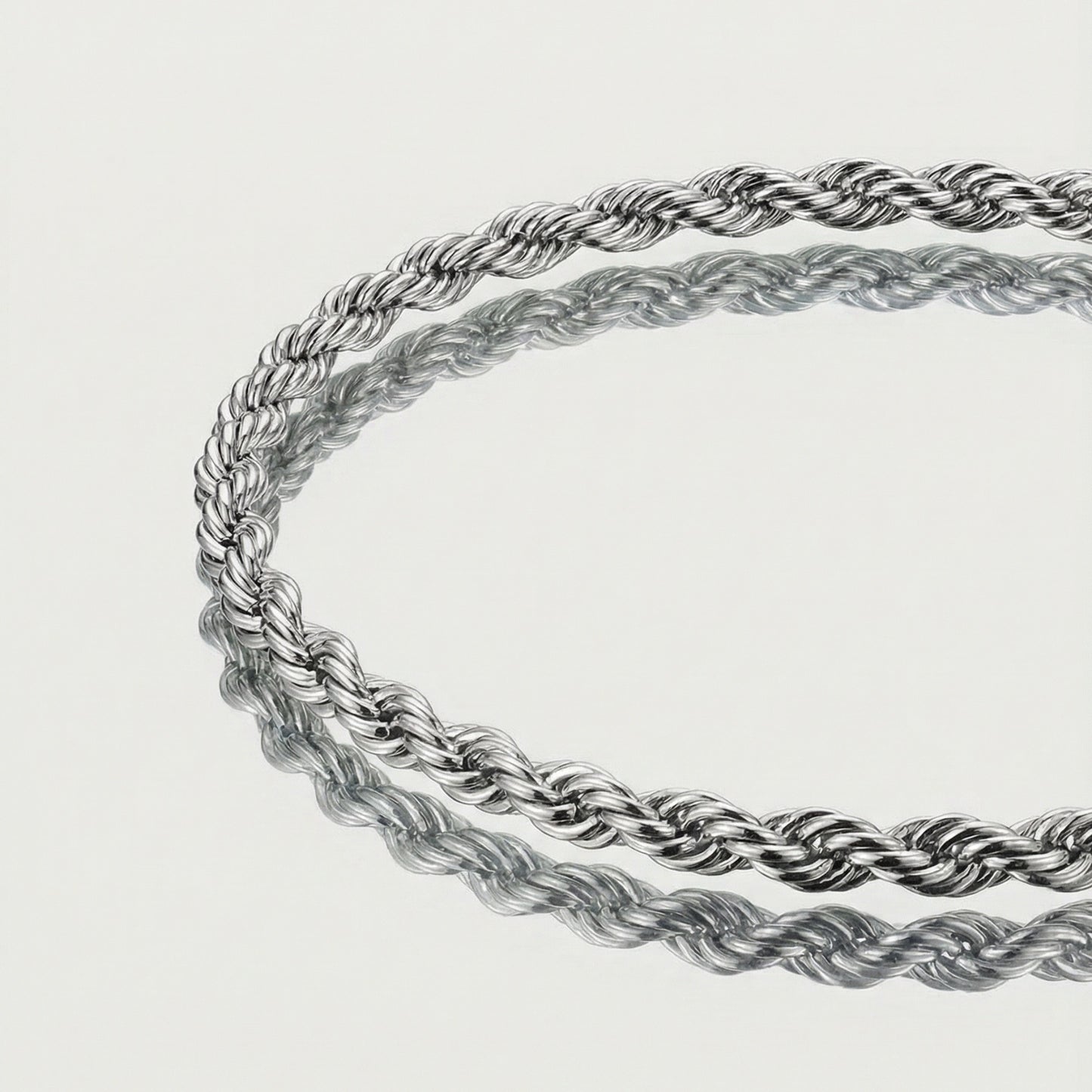 Two silver rope chains on a light gray background