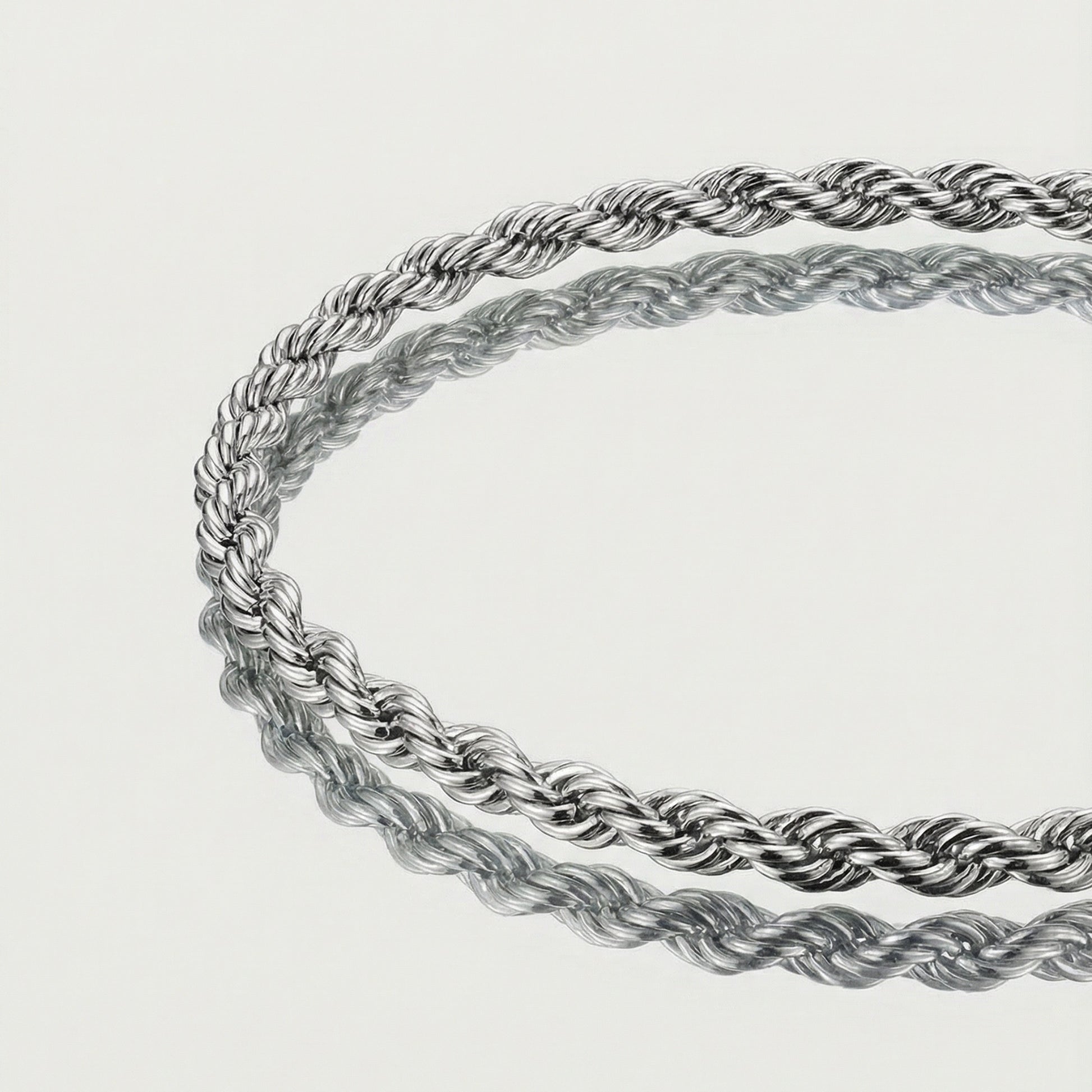 Two silver rope chains on a light gray background