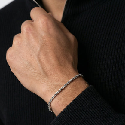 Close-up of a hand wearing a silver bracelet on a black background