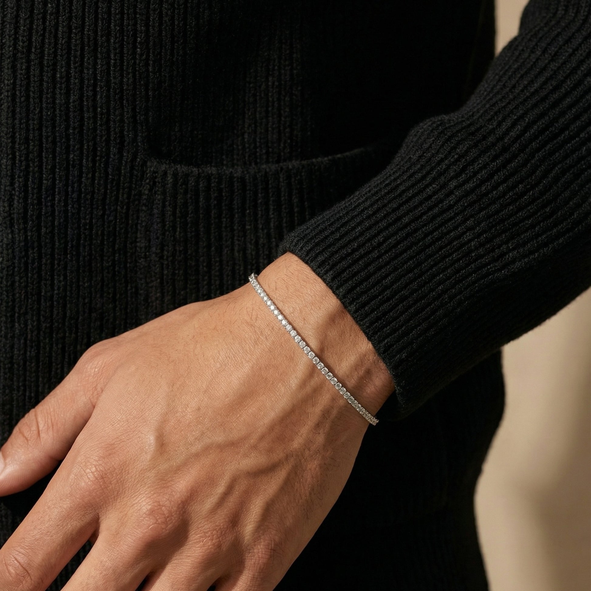 Close-up of a hand wearing a silver bracelet with a black sweater.