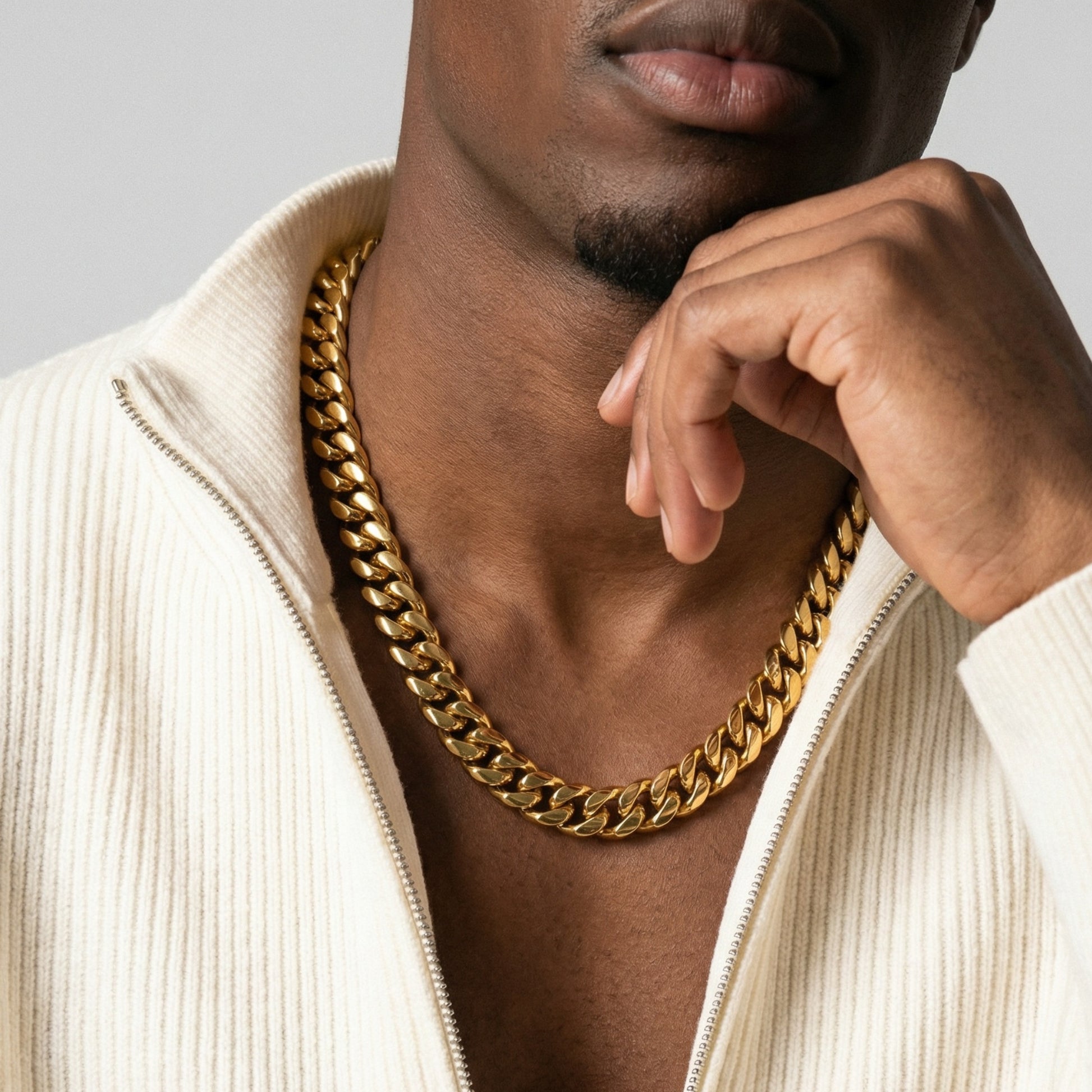 Man wearing a gold chain necklace with a neutral background