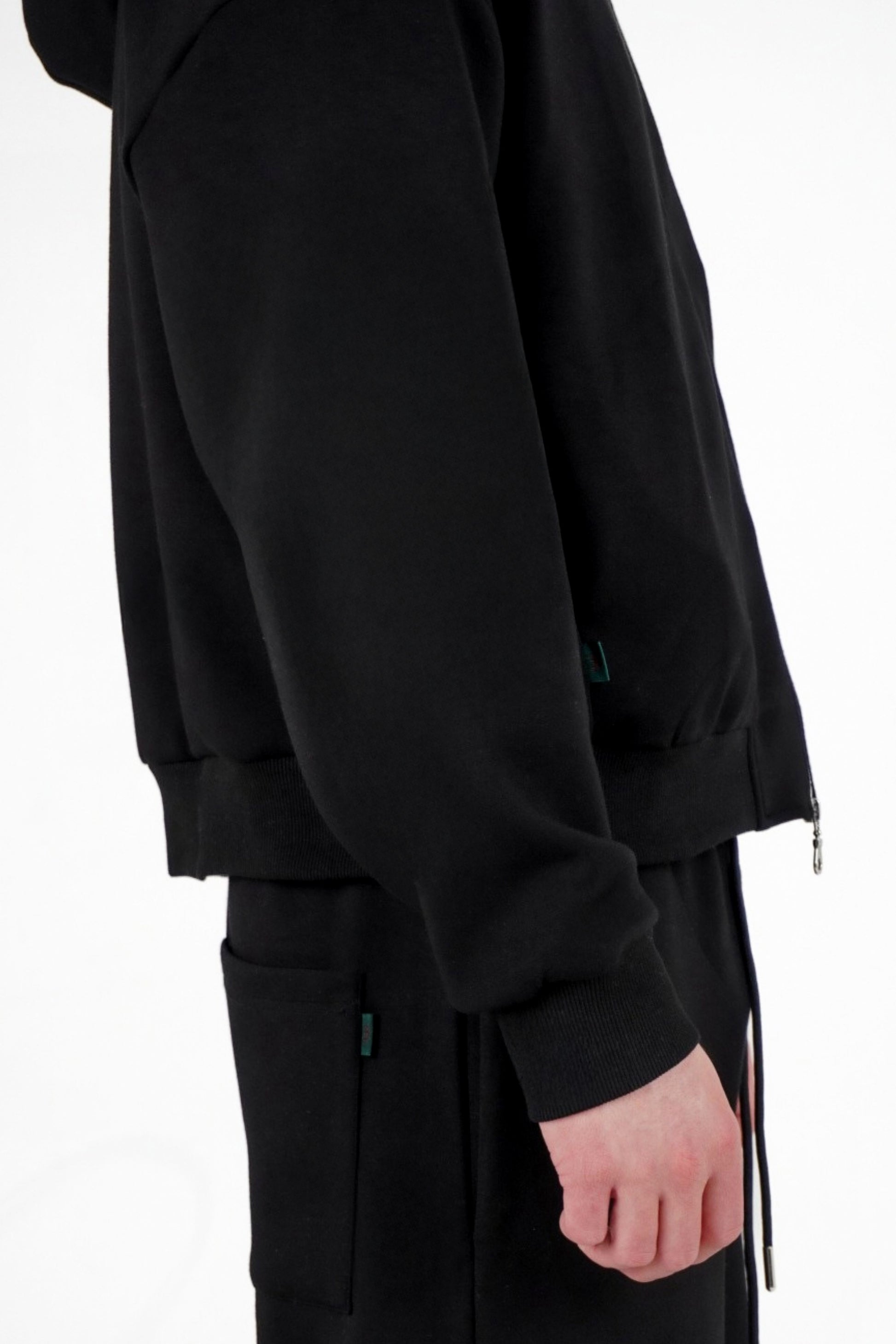 Black zip up worn by a person on a white background