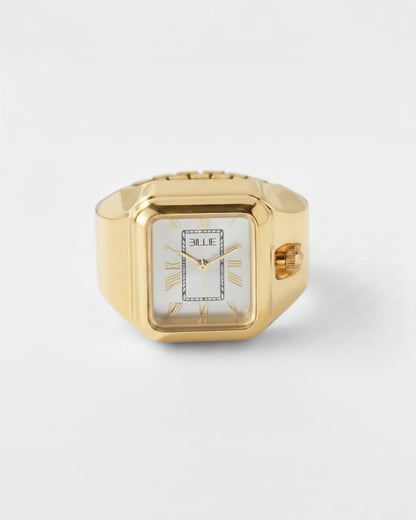 Billie Edge Ring Watch in gold, rectangular finger watch with white dial on a light background