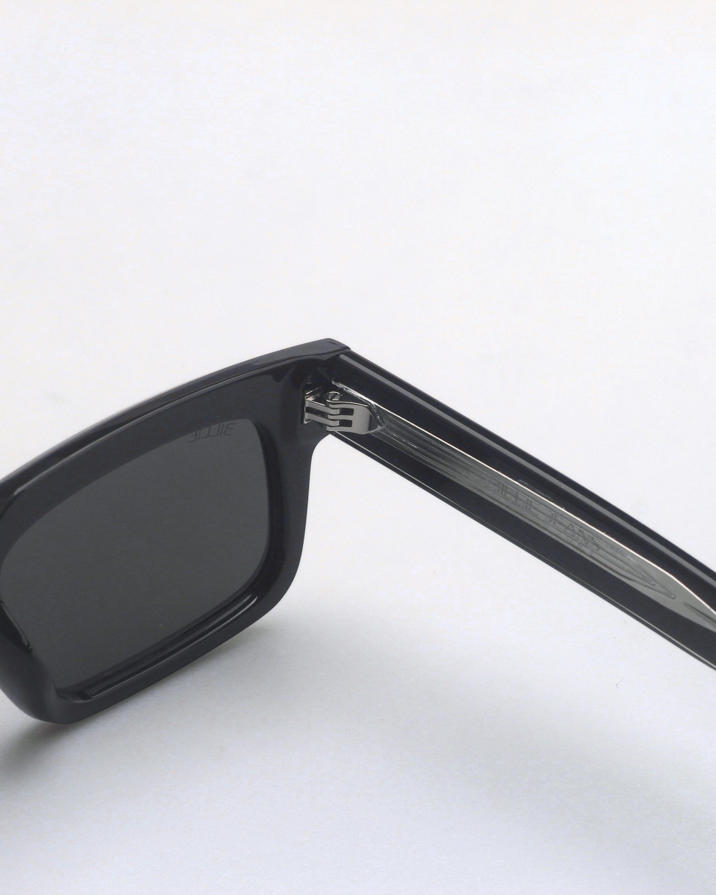 Close-up of black sunglasses with dark lenses and silver detailing on the arm.