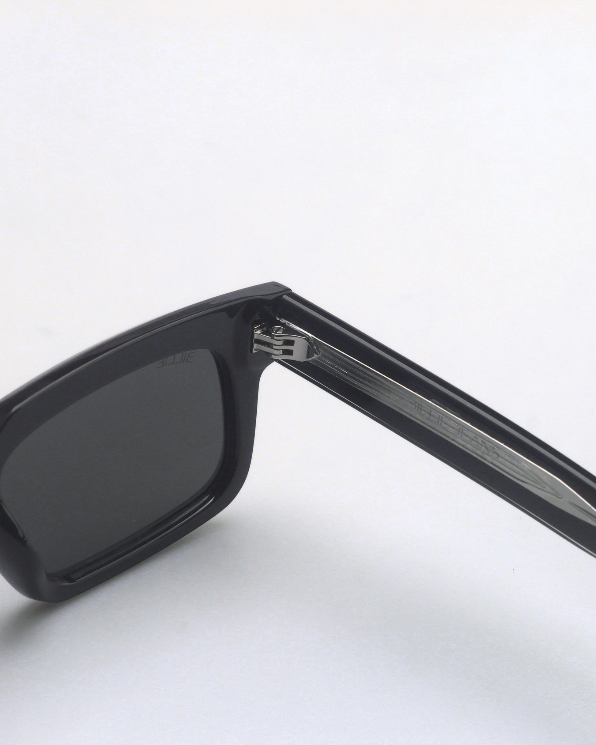Close-up of black sunglasses with dark lenses and silver detailing on the arm.