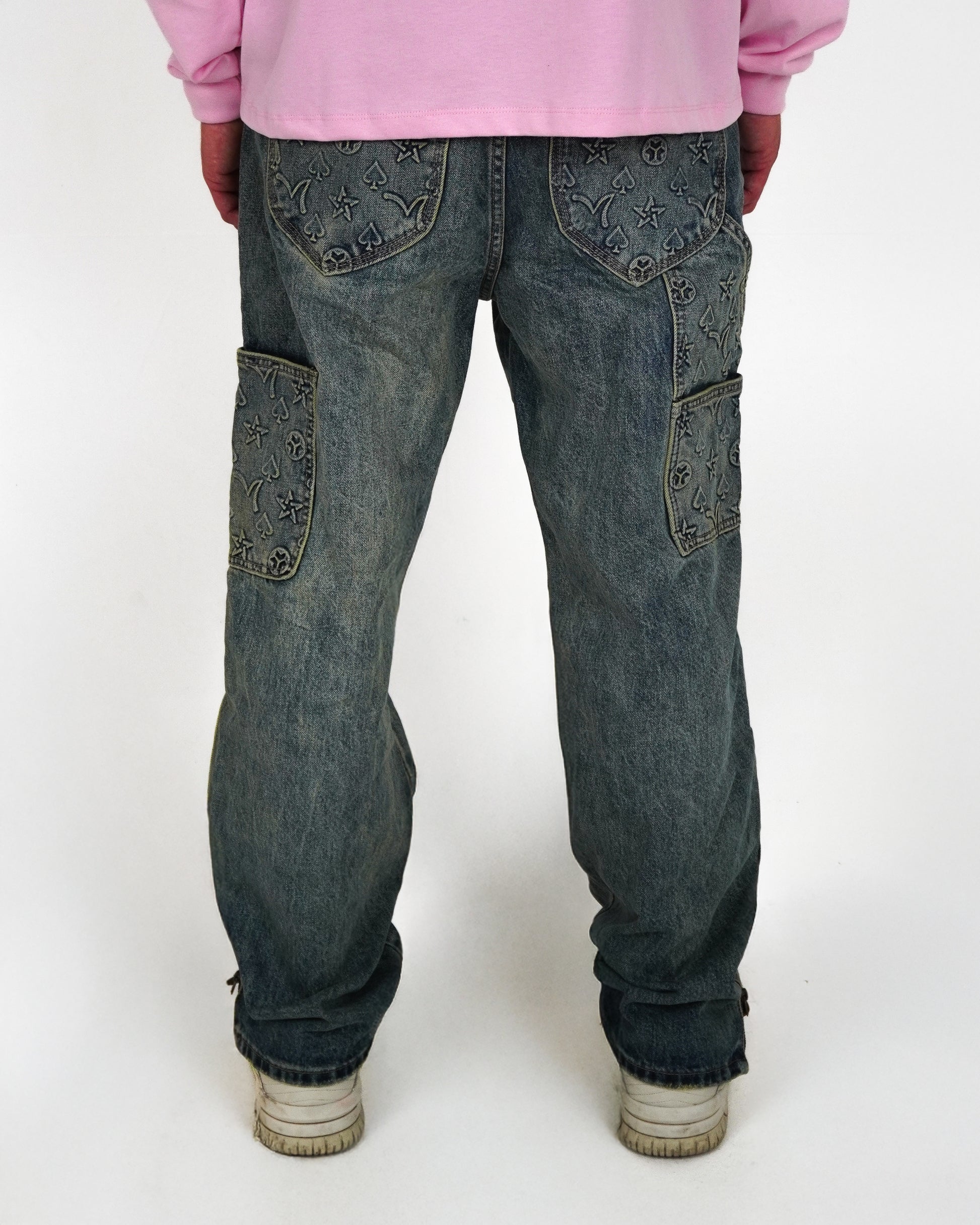 Back view of jeans with decorative patches and a pink long-sleeve shirt