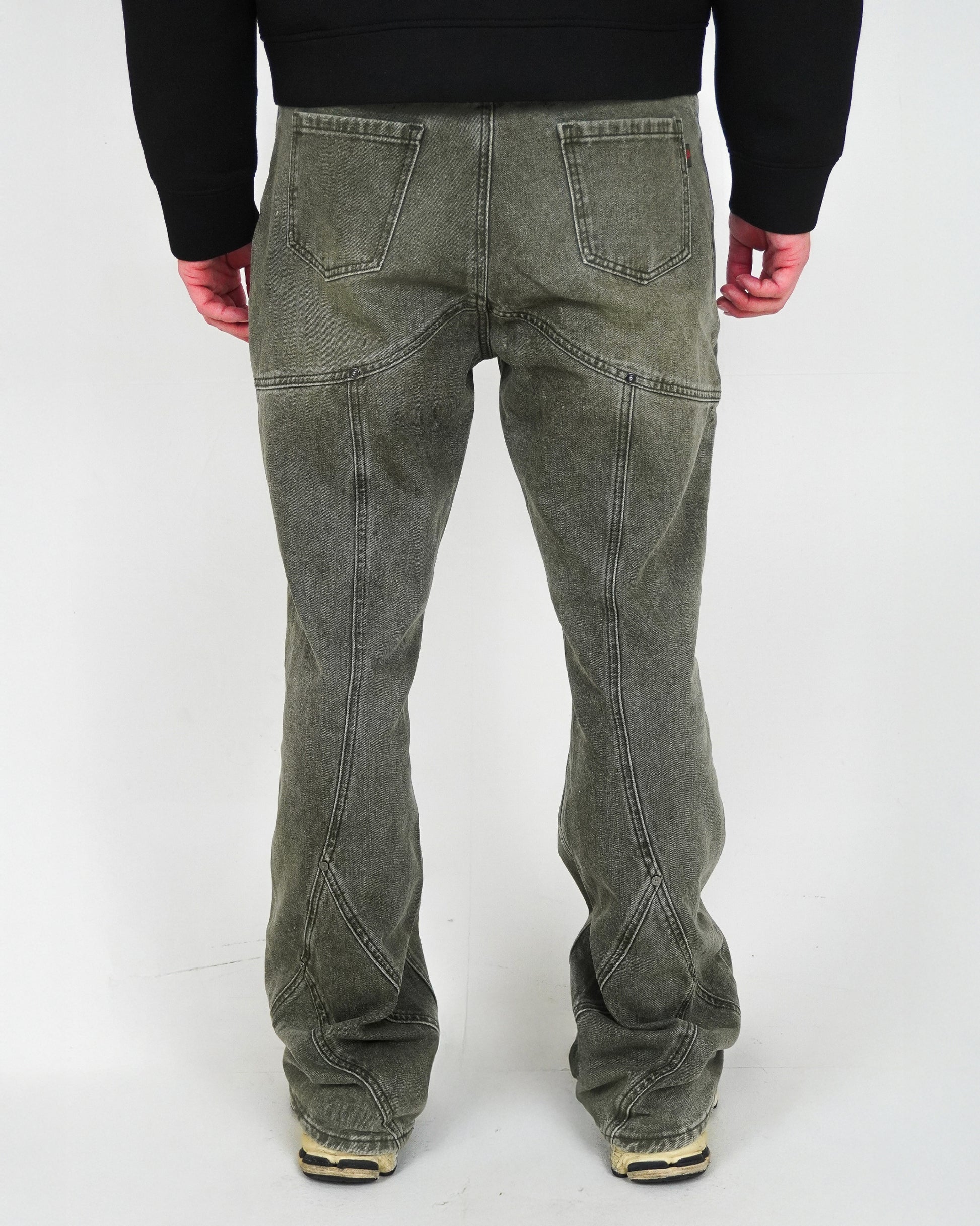 Back view of pants with visible stitching details, worn by a person with hands at their sides.