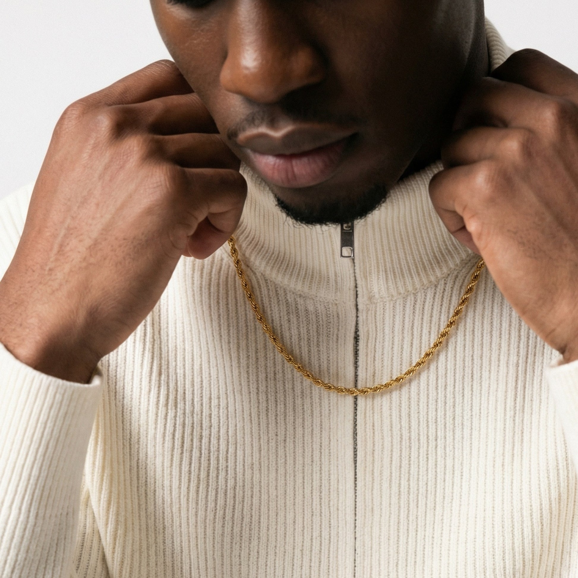 Person wearing a gold chain with a neutral background