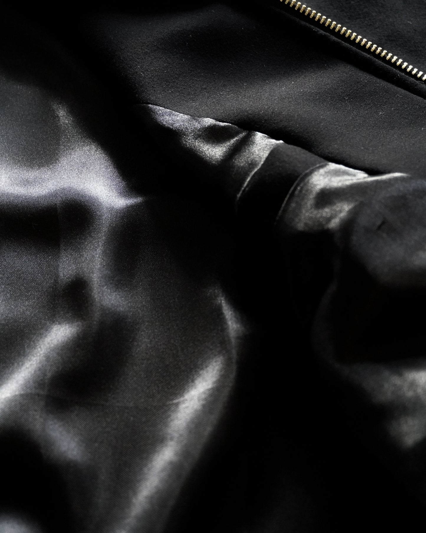 Close-up of black fabric with a smooth texture and a zipper.