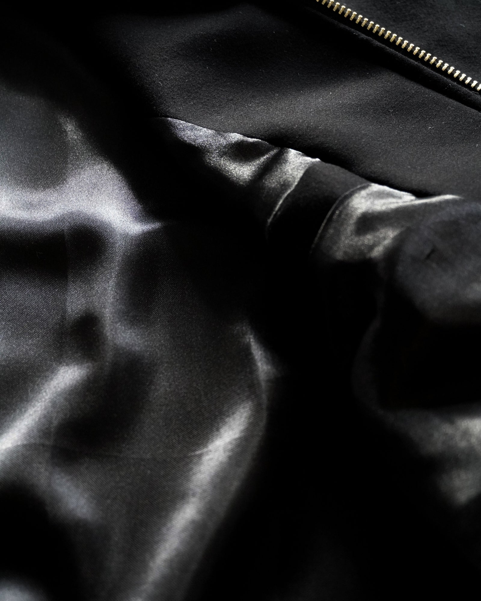 Close-up of black fabric with a smooth texture and a zipper.