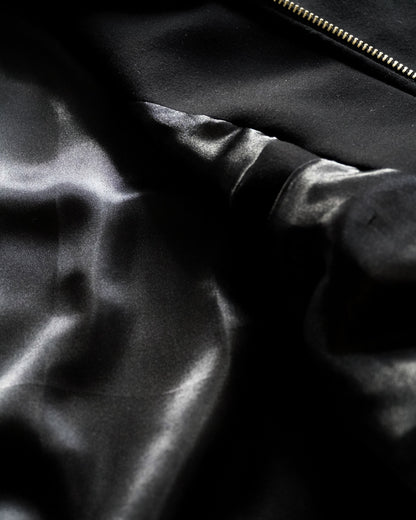 Close-up of black fabric with a smooth texture and a zipper.