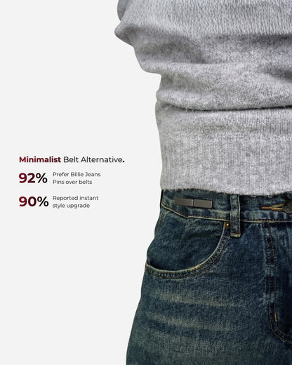 Close-up of a person wearing a gray sweater and dark jeans with a pin at the waist.