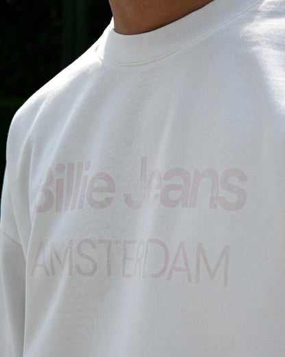 Close-up of a white shirt with faded text reading 'Billie Jeans AMSTERDAM'.