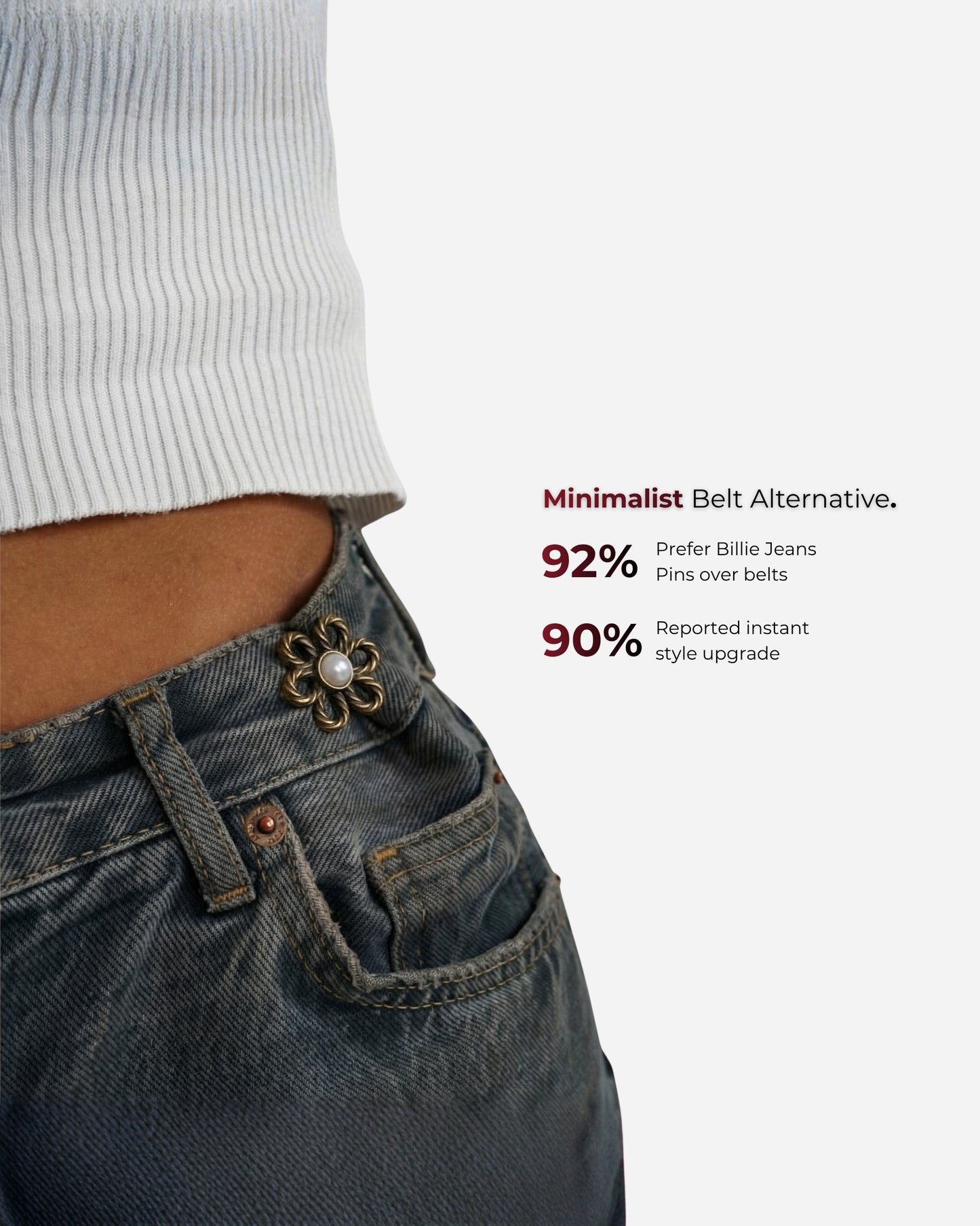 Close-up of a waist with a decorative pin on denim jeans and a white ribbed top.