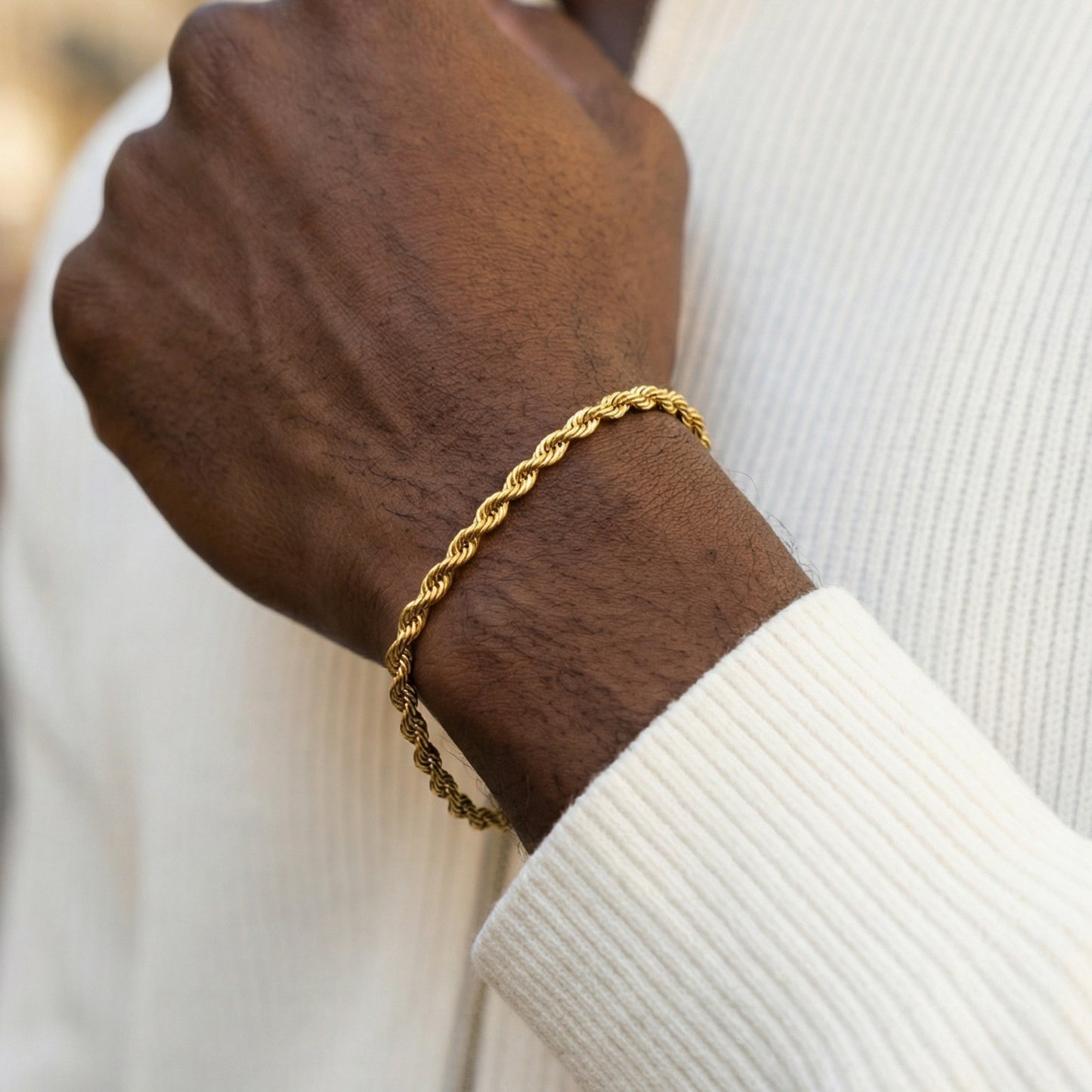 Gold rope chain bracelet on a wrist with a blurred background