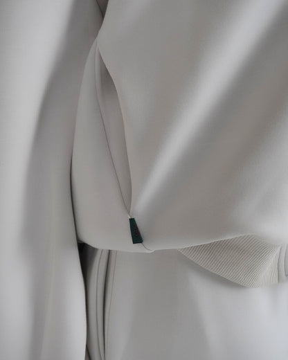 Close-up of a light gray garment with a visible tag and ribbed cuff.