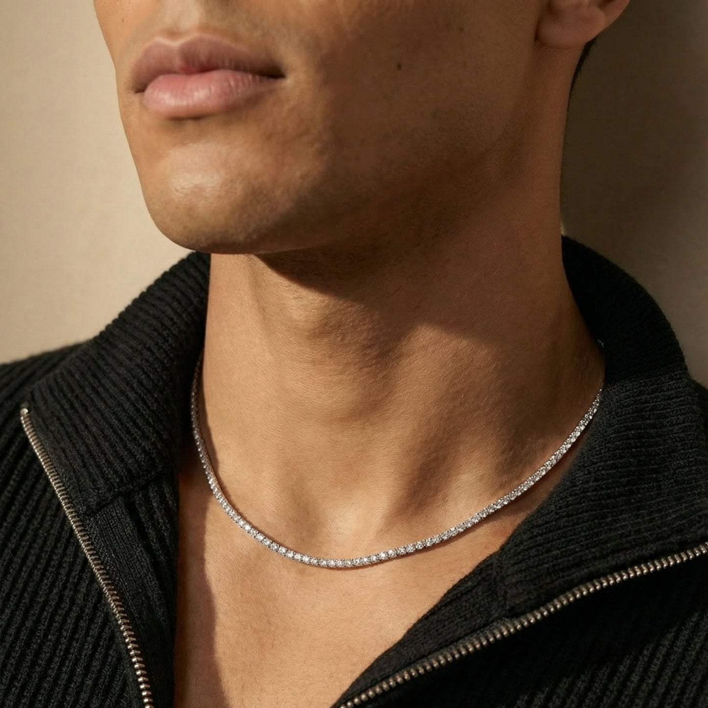 Close-up of a person wearing a silver necklace against a neutral background
