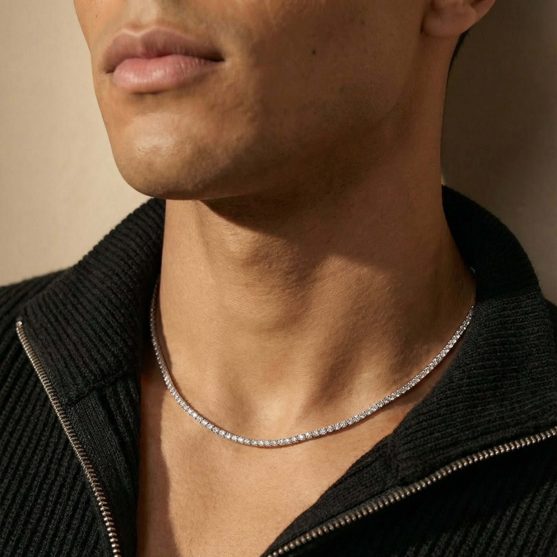 Close-up of a person wearing a silver necklace against a neutral background