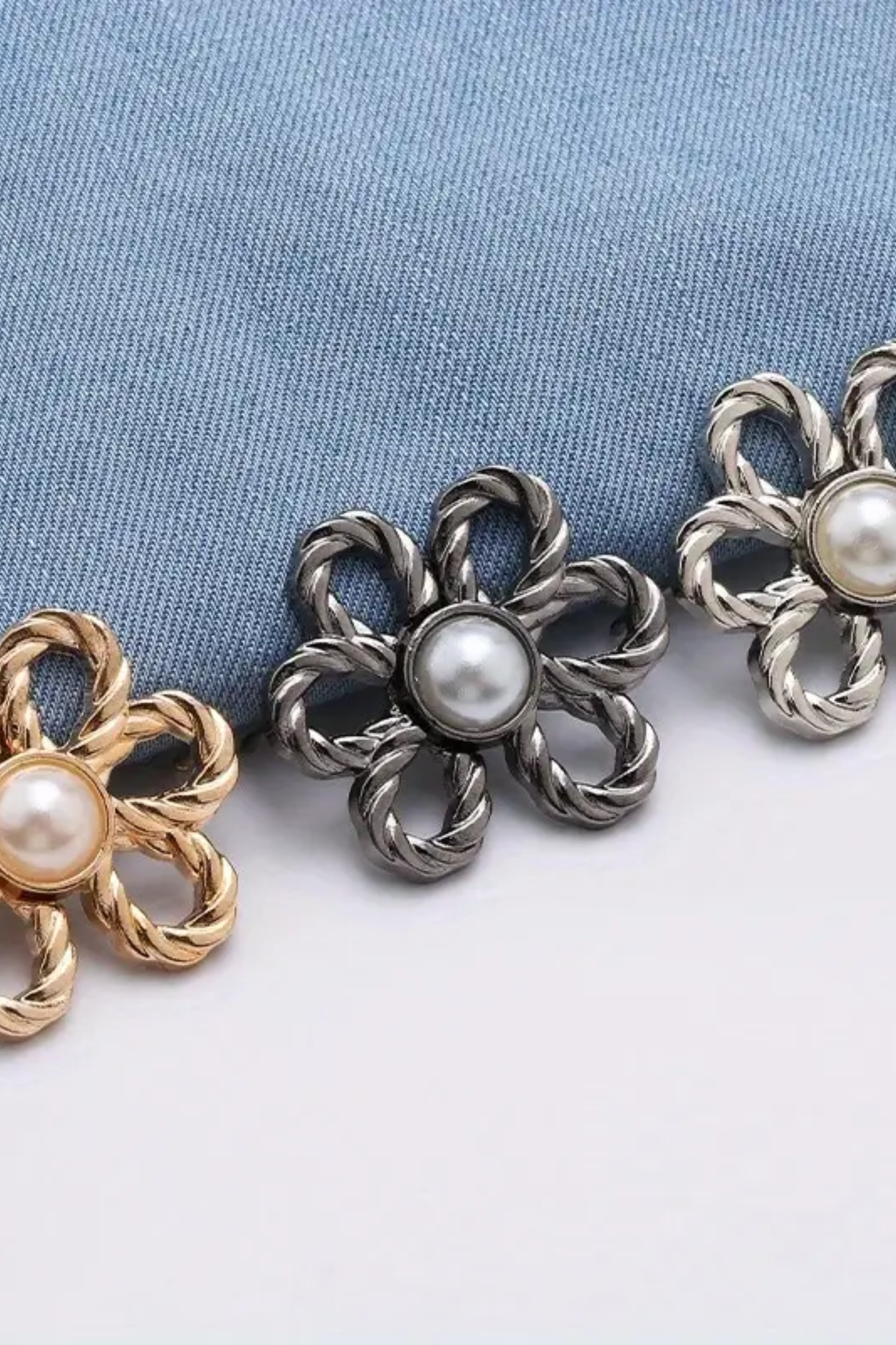 Three waist knots with pearl centers on a light blue fabric background