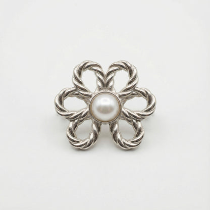 Silver brooch with a central pearl on a white background
