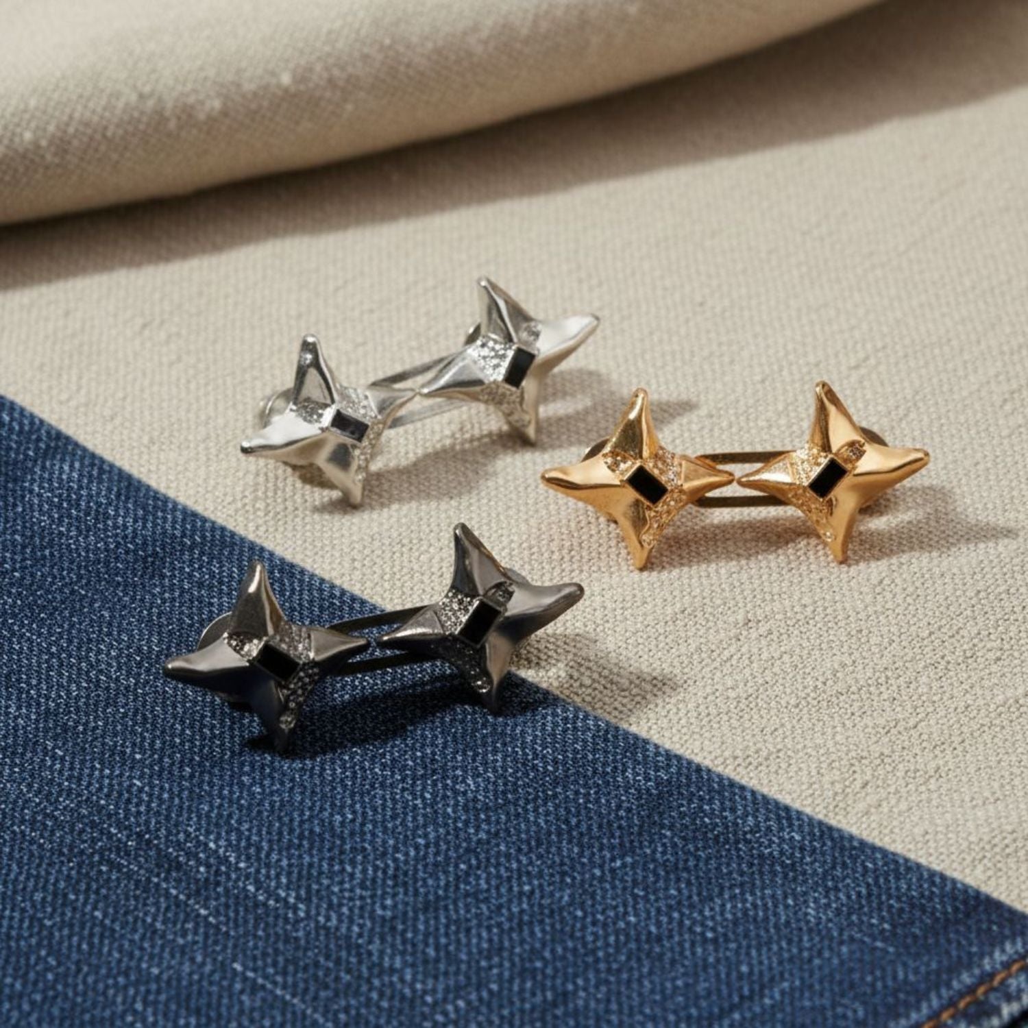 Three pairs of star-shaped waist knots in silver, gold, and black on a textured fabric background.