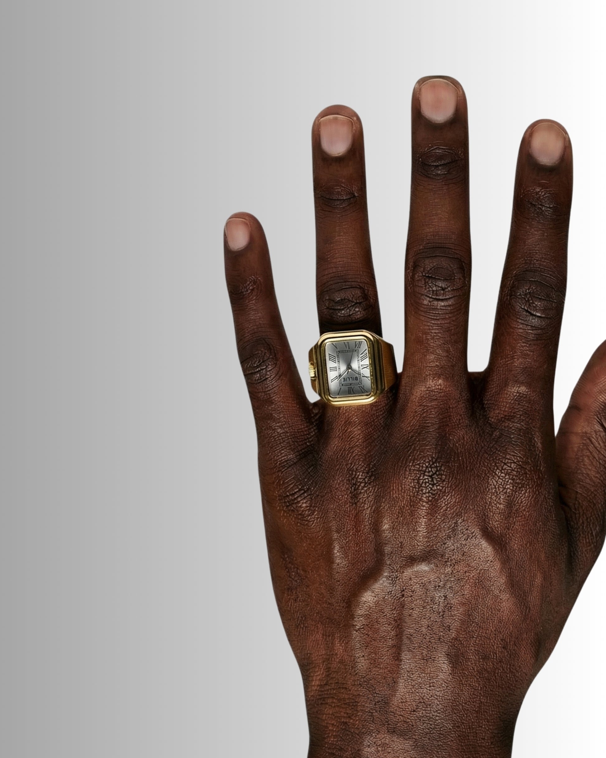 Close-up of a hand wearing a gold ring and a watch on a gradient background.