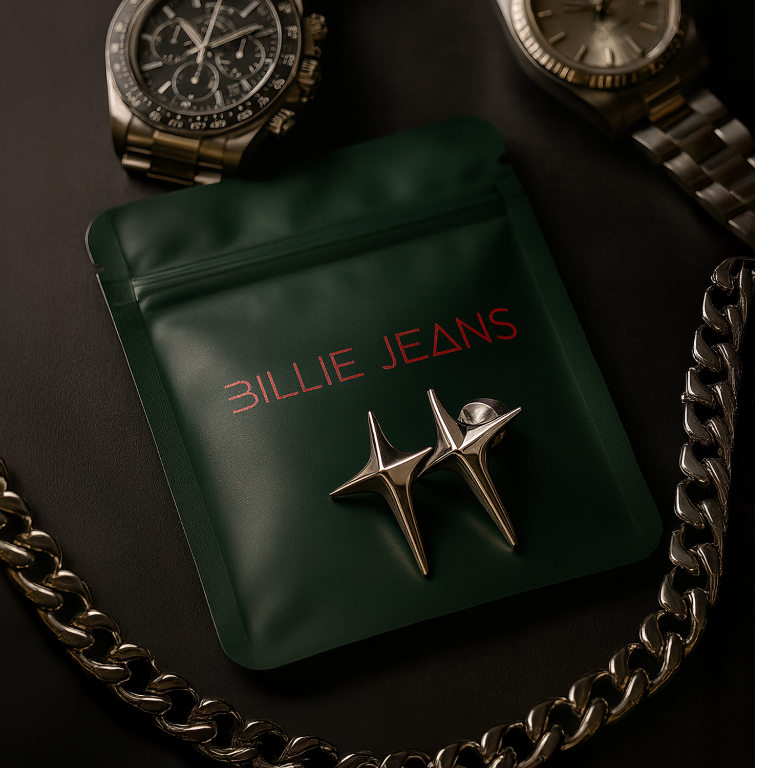 Green packaging with 'Billie Jeans' branding and star-shaped pins, surrounded by watches and a chain on a dark surface.