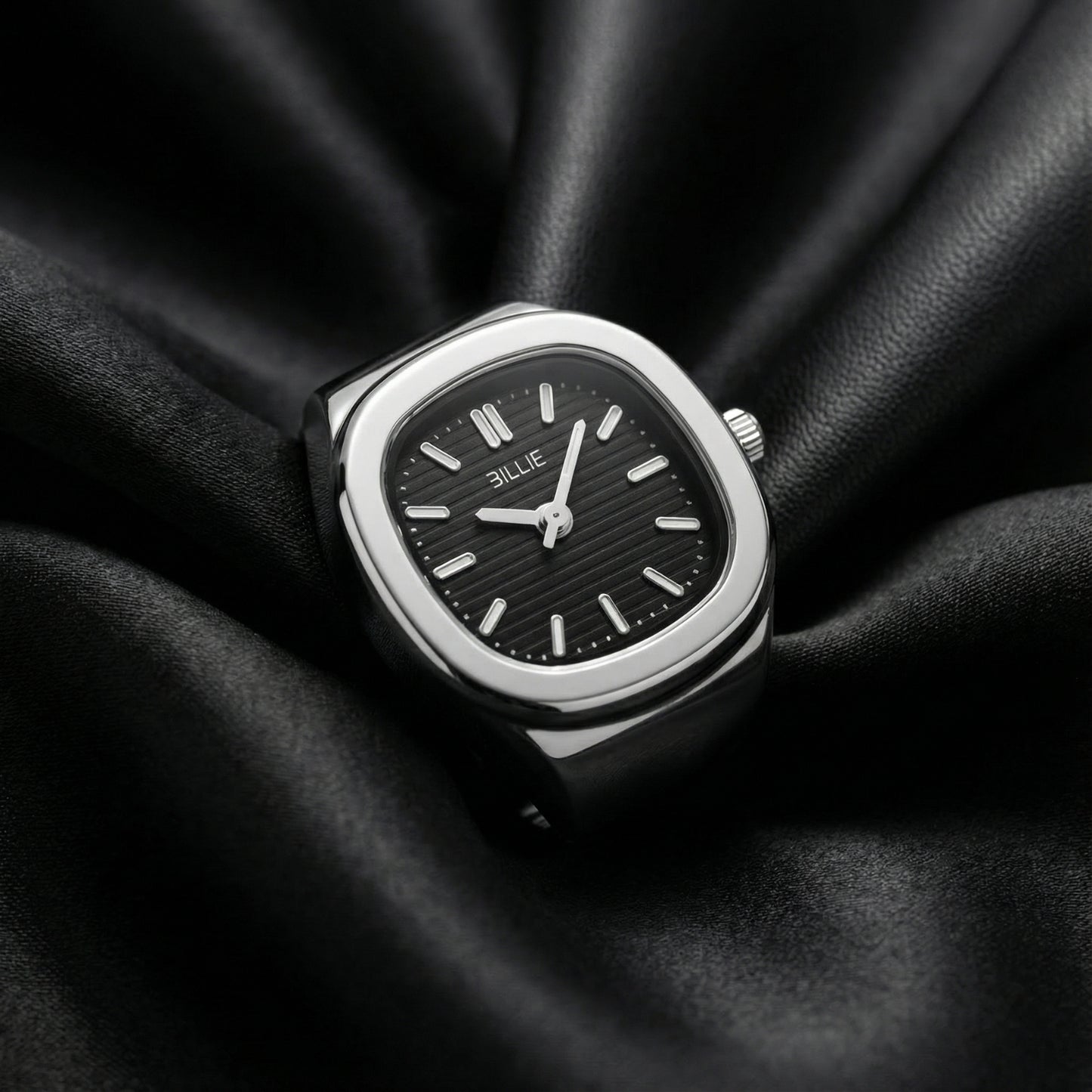 Silver watch with black face on a black fabric background