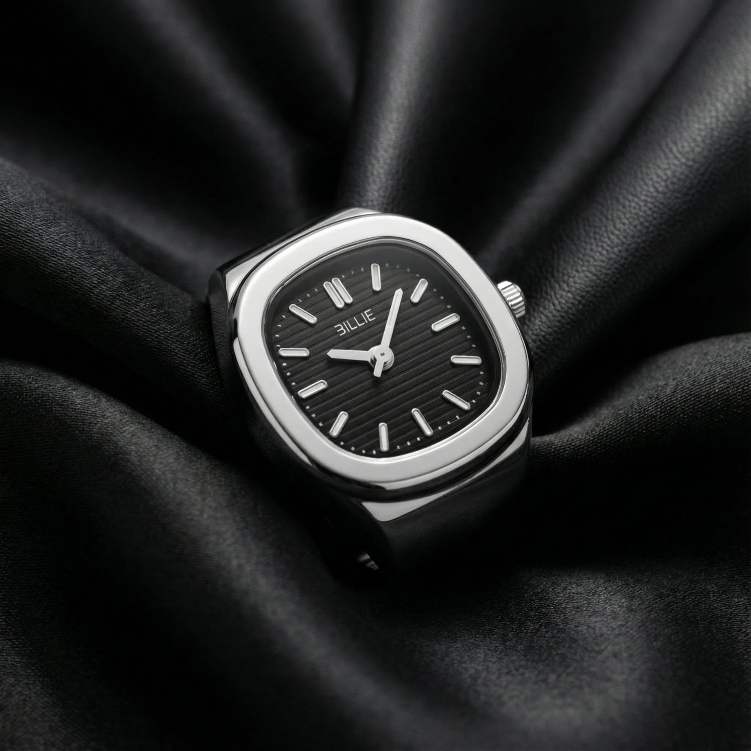 Silver watch with black face on a black fabric background