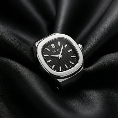Silver watch with black face on a black fabric background