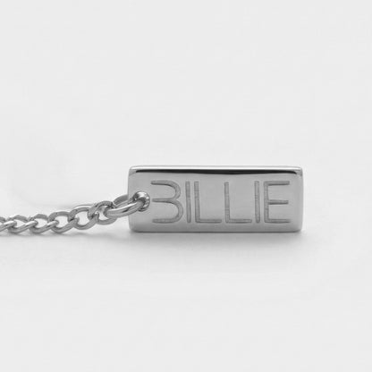 Silver necklace with a rectangular tag engraved with 'BILLIE' on a white background