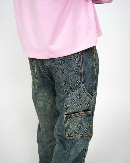 Person wearing a pink long-sleeve shirt and patterned denim jeans.
