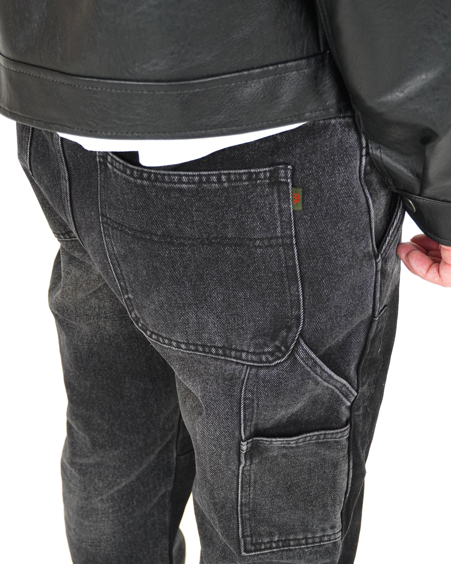 Close-up of the back of black denim pants with pockets and a leather jacket.