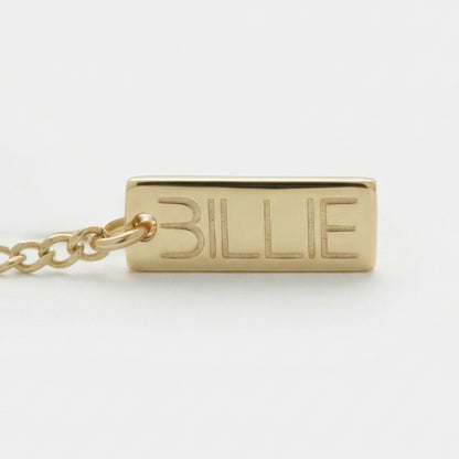 Gold pendant with 'BILLIE' engraved on a white background