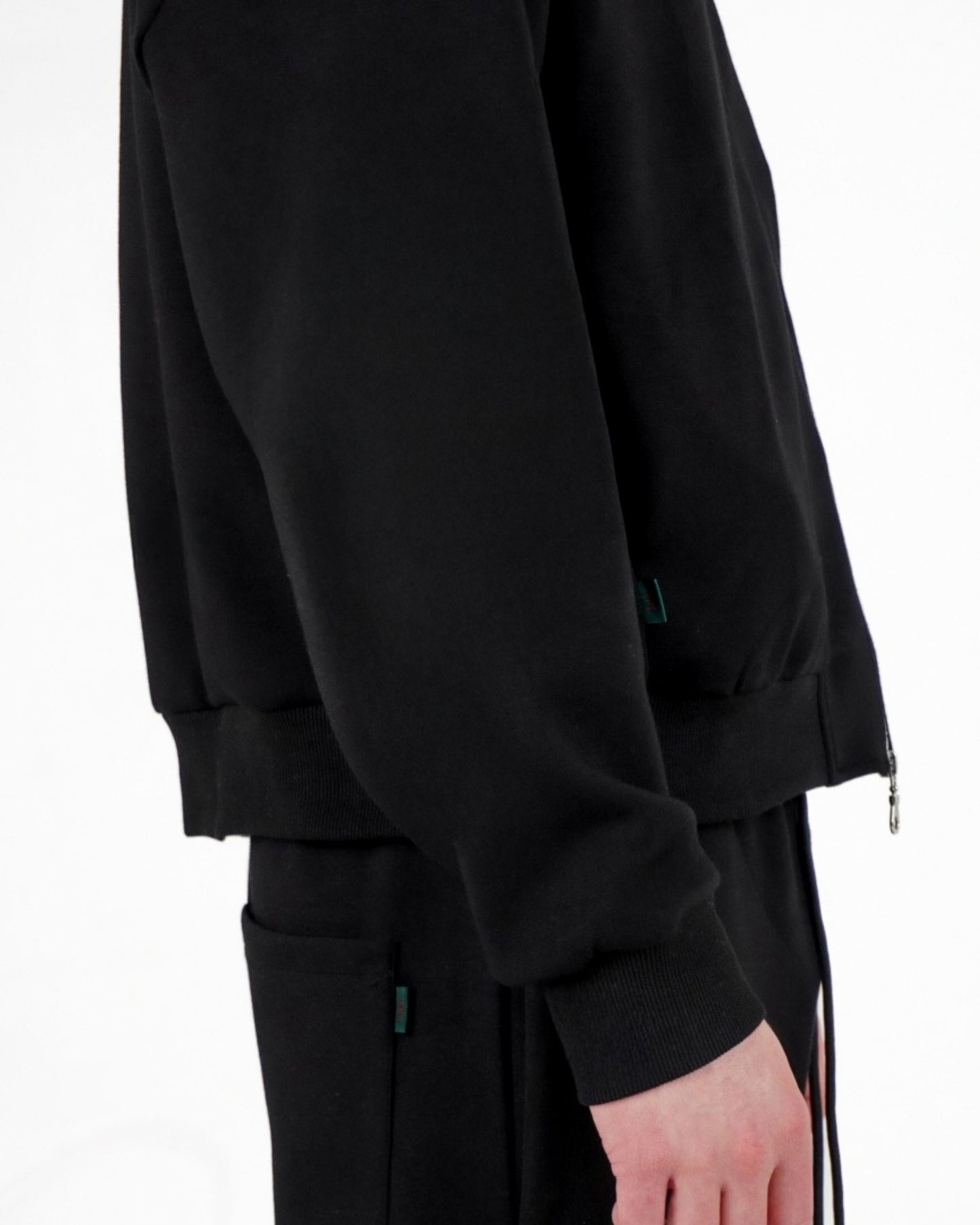 Side view of a black sweatshirt with a zipper and matching pants on a plain background.