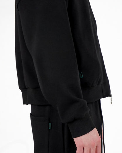 Side view of a black sweatshirt with a zipper and matching pants on a plain background.