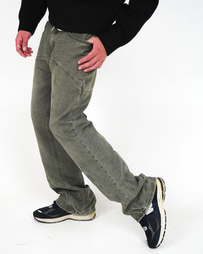 Person wearing green pants and black sneakers, standing on a plain background.