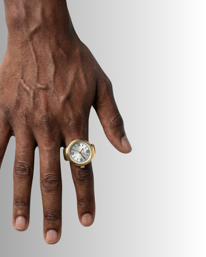 Close-up of a hand wearing a gold ring and a watch with a white face.