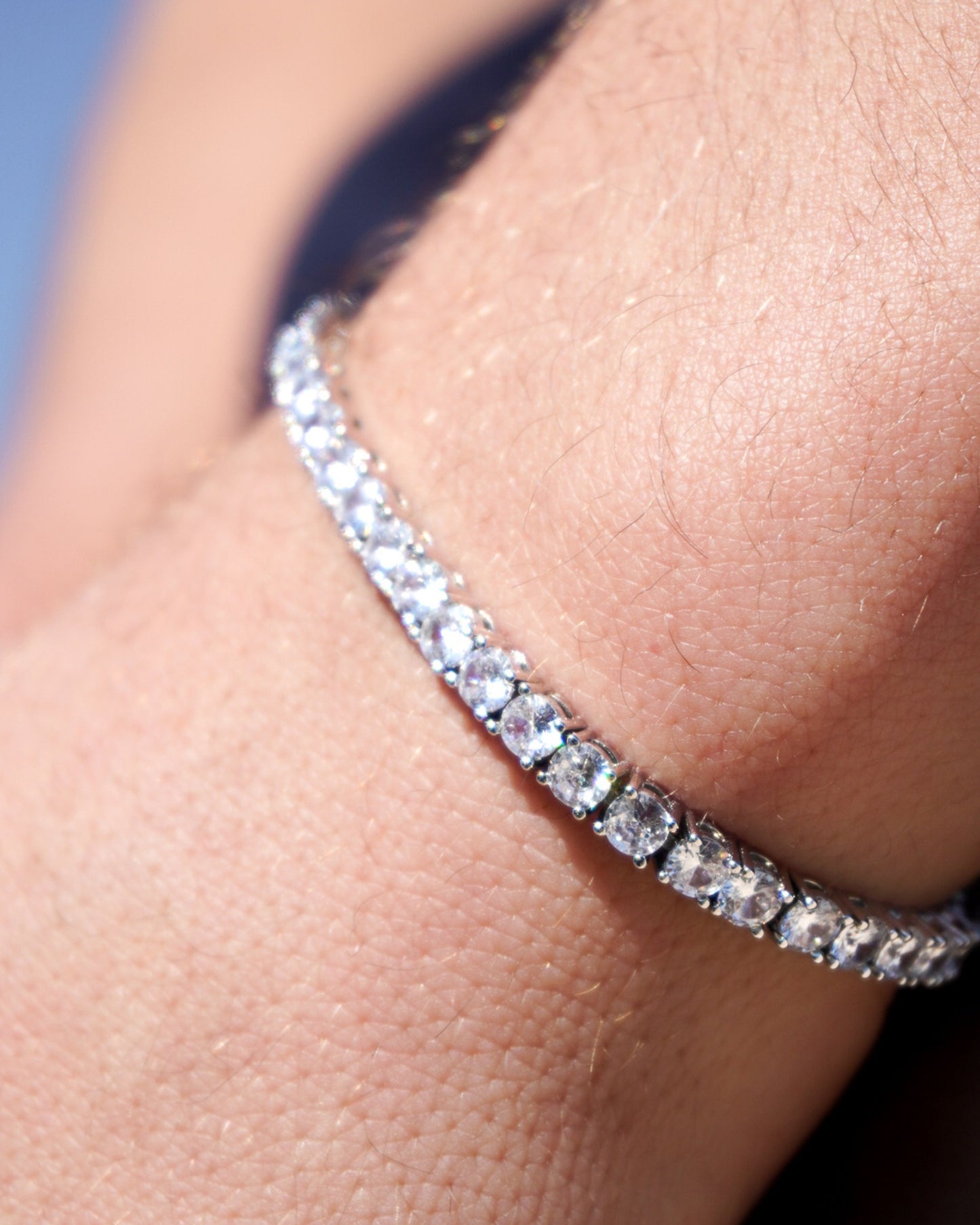 Close-up of a hand wearing a shiny bracelet with clear stones.