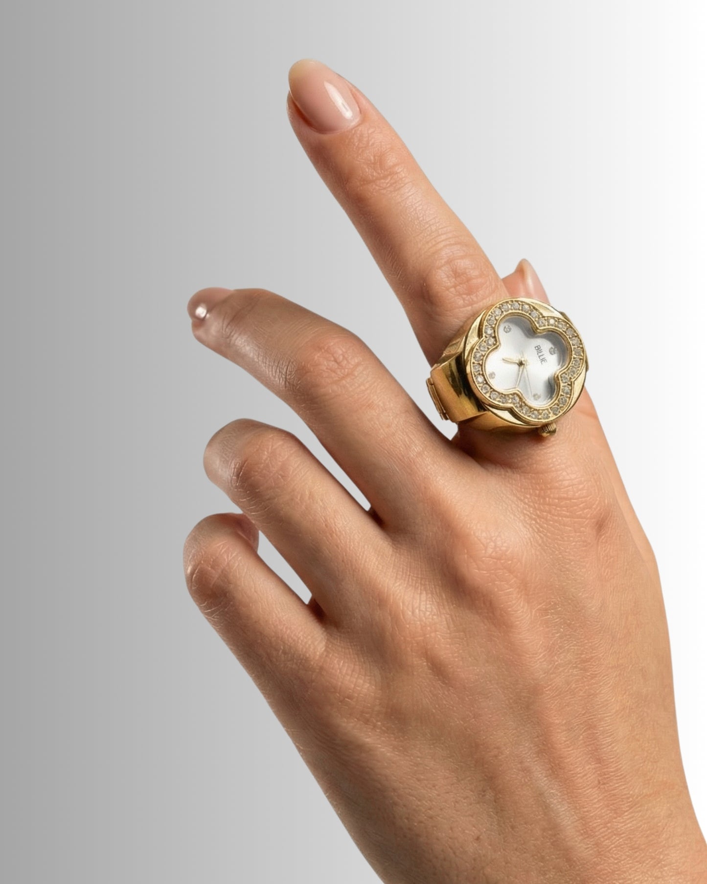 Hand with a gold ring featuring a white clock face and decorative details.