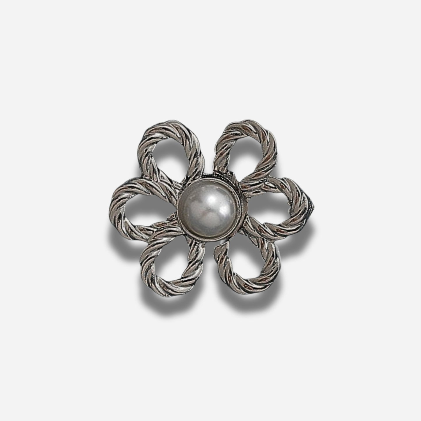 Zilveren bloemvormige broche met een centrale parel op een lichtgrijze achtergrond
