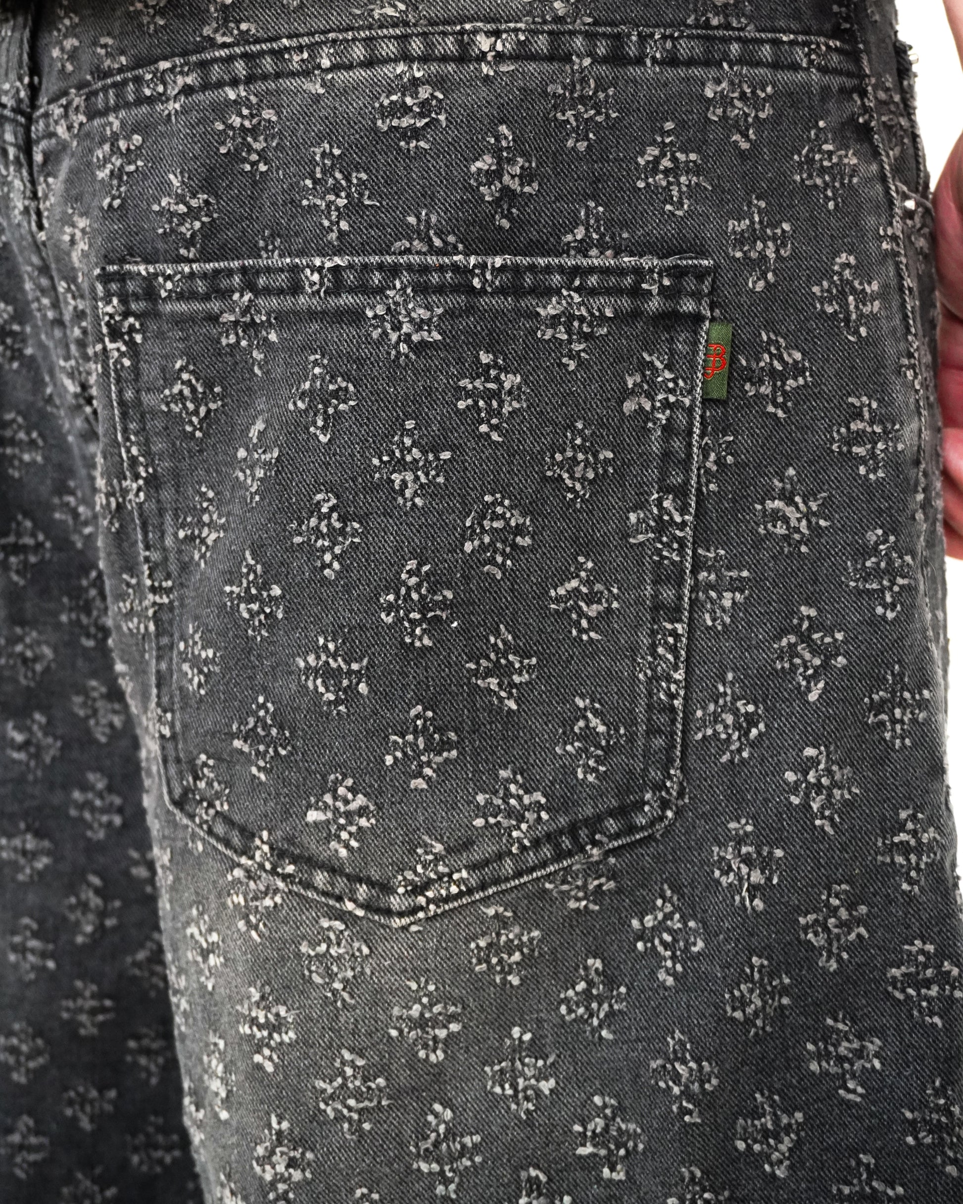 Close-up of a patterned back pocket on dark denim fabric.