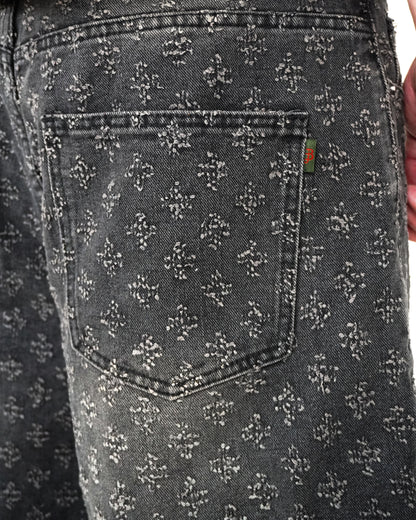 Close-up of a patterned back pocket on dark denim fabric.