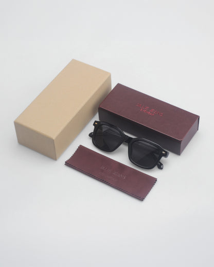 Black sunglasses with a cleaning cloth and two boxes, one beige and one maroon.