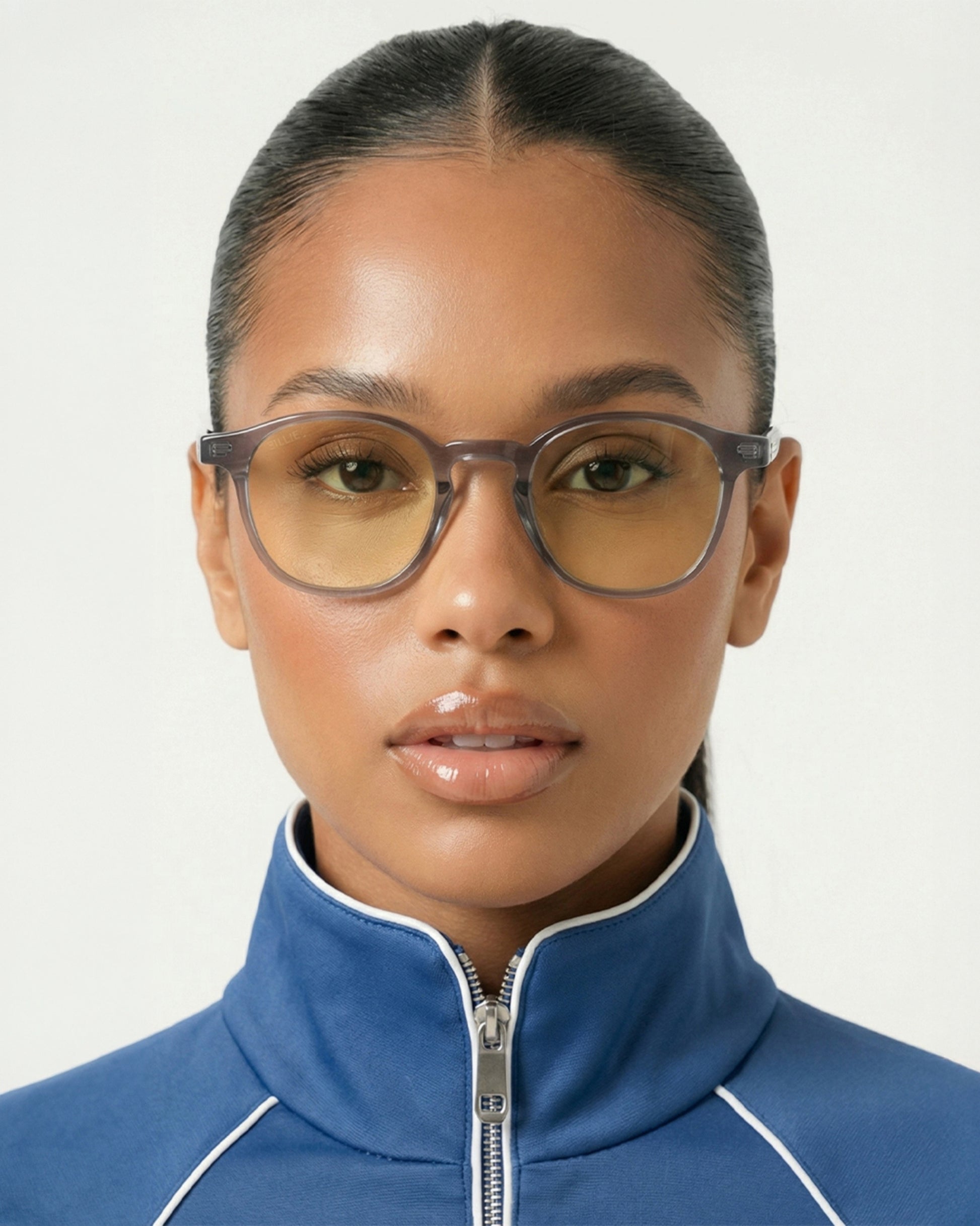 Person wearing glasses and a blue zip-up jacket with a high collar.