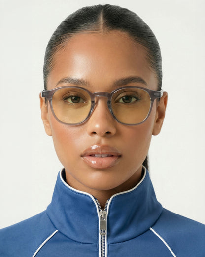 Person wearing glasses and a blue zip-up jacket with a high collar.