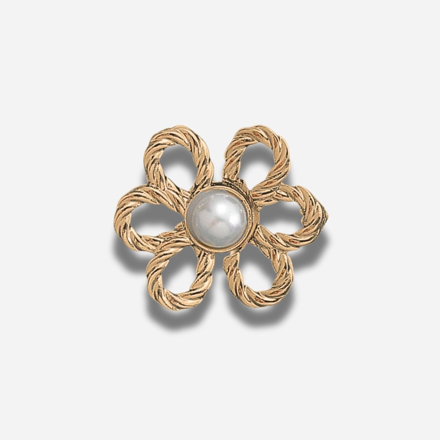 Gouden bloemvormige broche met een centrale parel op een lichtgrijze achtergrond